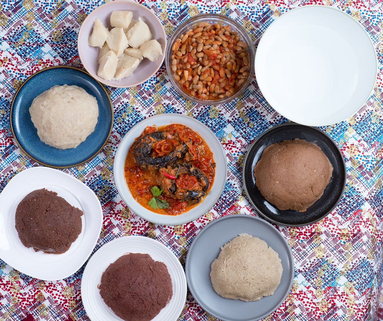 A vibrant flat lay of traditional Burundian dishes including ugali, beans, and vegetable sauce.